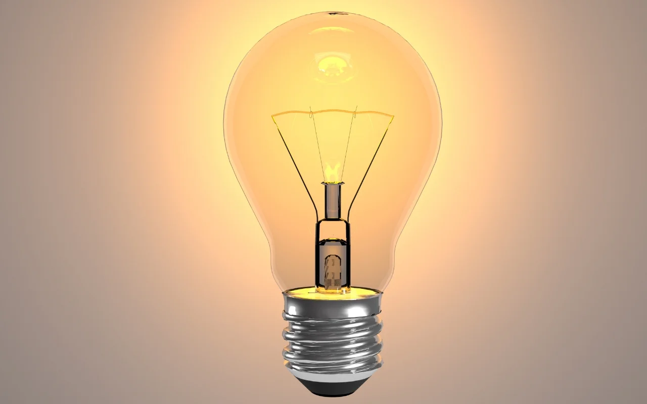 A glowing incandescent lightbulb with a visible filament is illuminated, emitting a warm, energy-filled yellow-orange light against a neutral background.